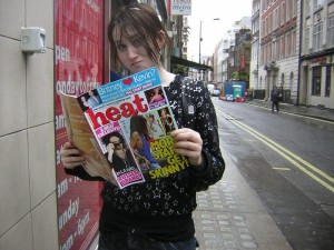 She is reading Heat magazine in the street